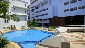 A swimming pool with a blue tiled border, surrounded by a stone deck and potted plants.