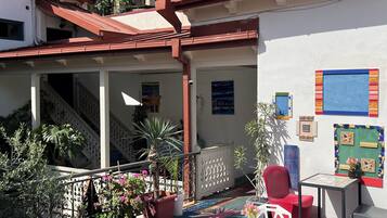 A courtyard with a colorful floor, white chairs, a small table, and potted plants.