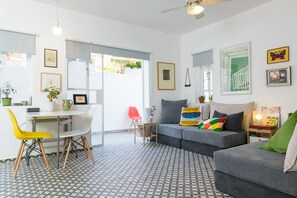 A modern living room with a grey sofa, a dining table with chairs, and a patterned floor.