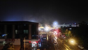 A nighttime street view with a supermarket and a brightly lit building in the background. - Eriza Hotel (Erzincan)