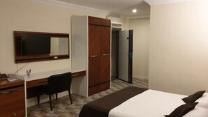 Une chambre d’hôtel équipée d’un lit, d’un bureau, d’une chaise, d’une armoire et d’un téléviseur fixé au mur.