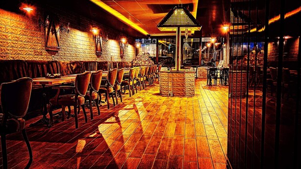 Un restaurant doté d’un plancher en bois, de murs en briques et d’un espace central avec des tables et des chaises.