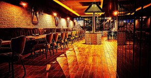A restaurant with wooden flooring, brick walls, and a central seating area with tables and chairs. - Eriza Hotel (Erzincan)