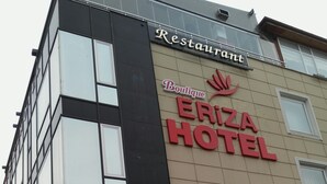 Un bâtiment sur lequel on peut lire l’inscription « HÔTEL ERIZA » et, juste au-dessus, « Restaurant-boutique ».