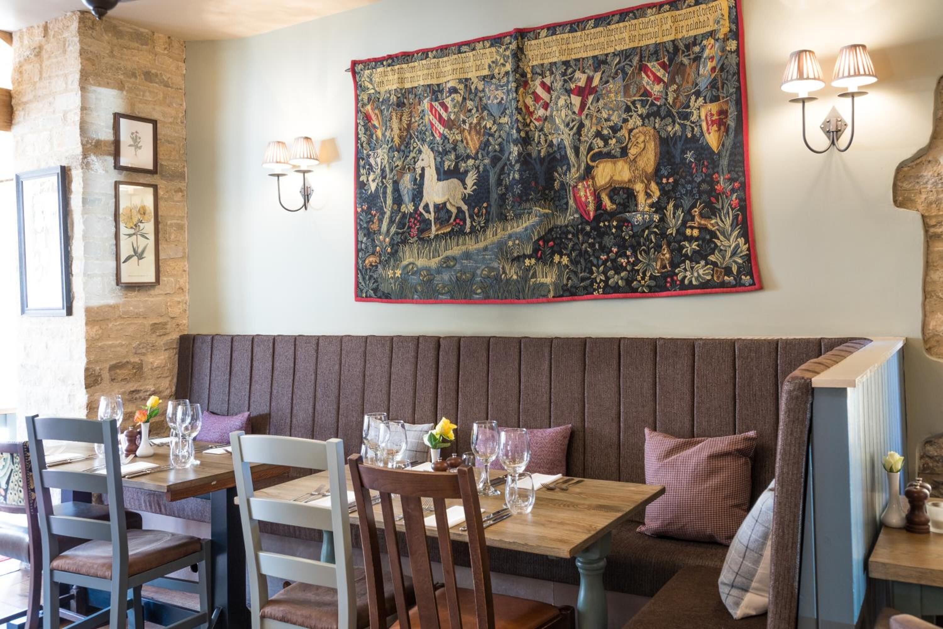 Un restaurante con mesas y bancos de madera, obras de arte enmarcadas en la pared y lámparas fijadas a la pared.