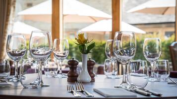 A table set for dining with wine glasses, a vase with a yellow flower, and salt and pepper shakers.