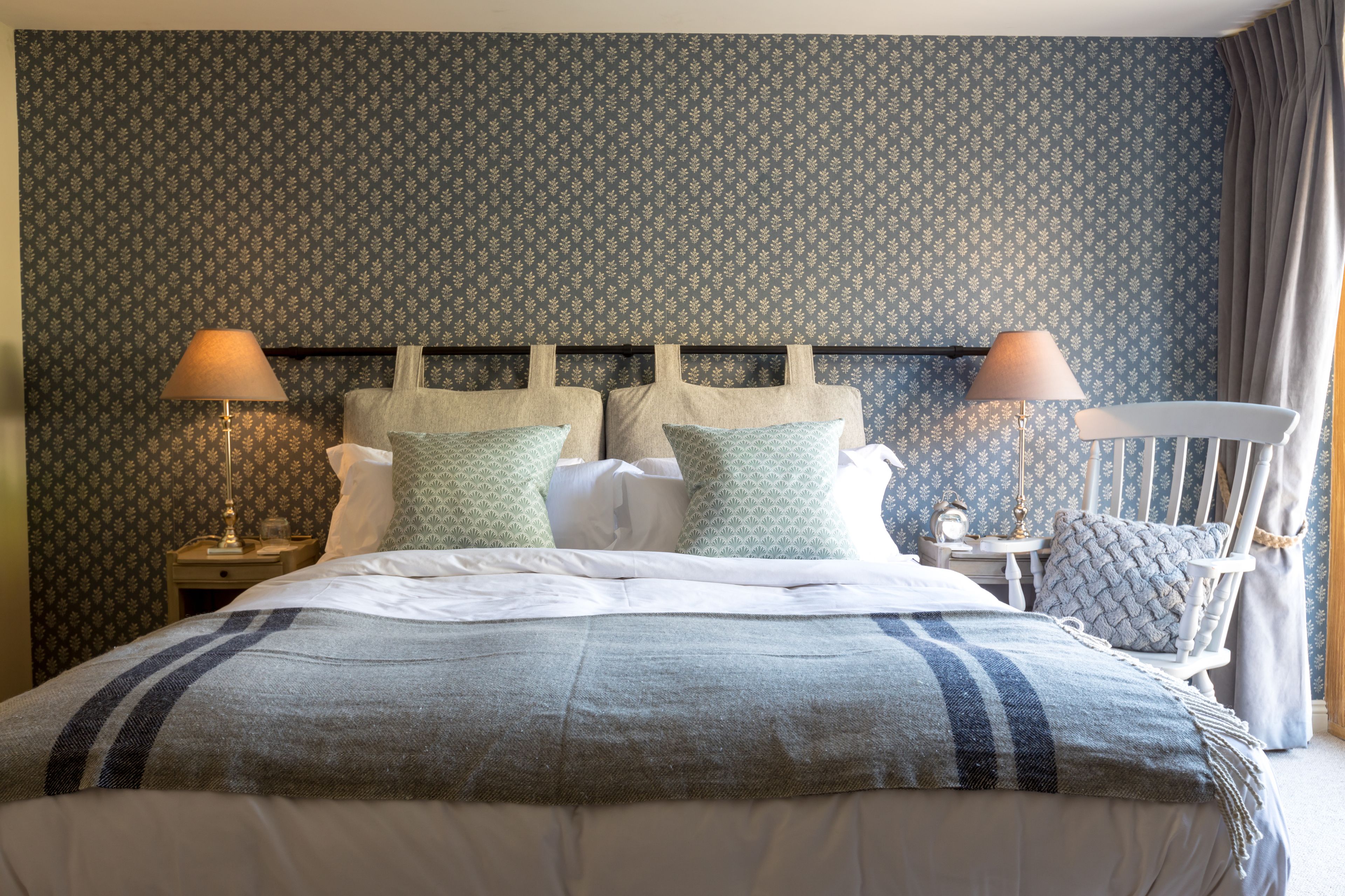 A neatly made bed with a striped blanket, two bedside lamps, and a nightstand with a lamp.