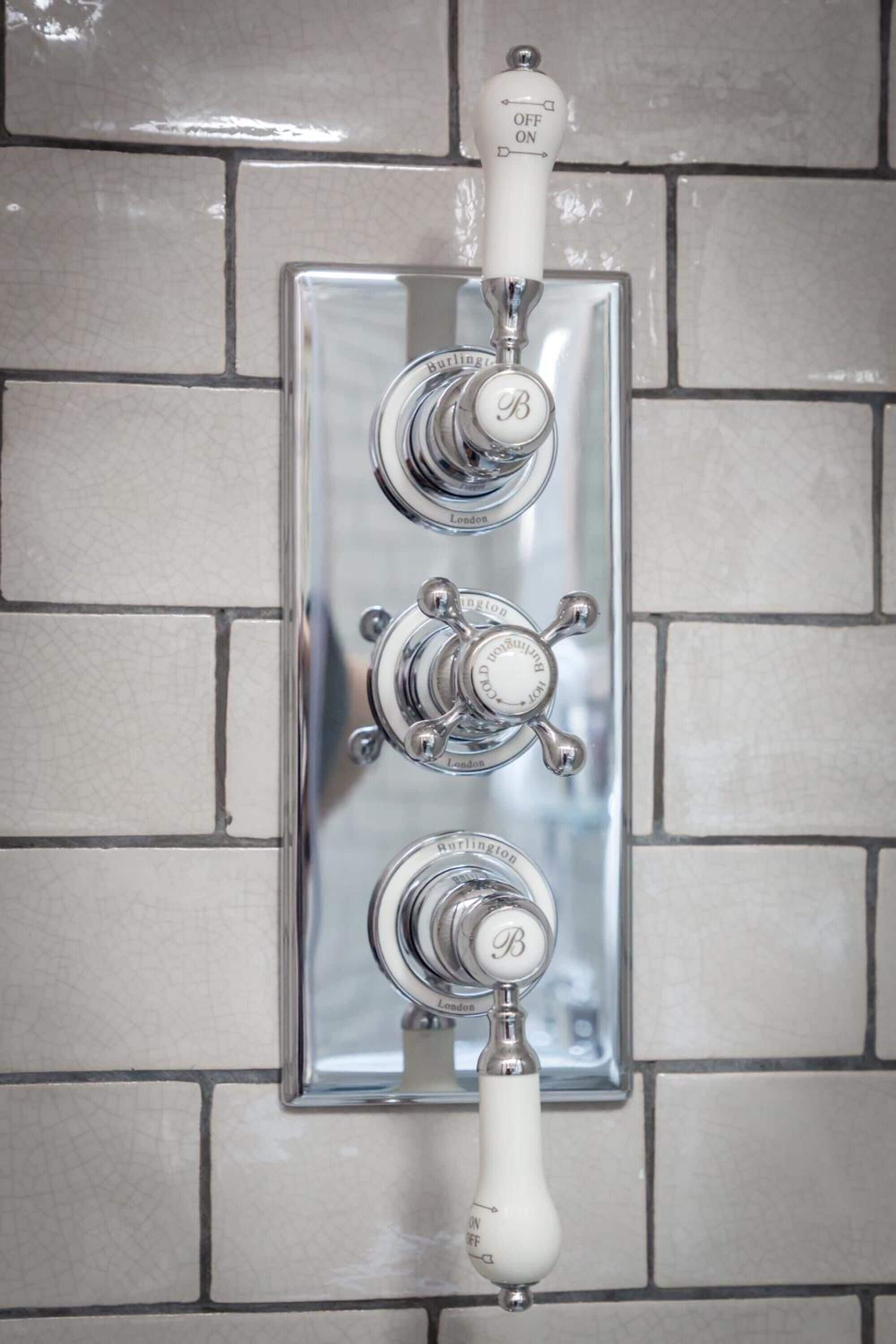 A bathroom with a chrome faucet and a wall-mounted control panel.