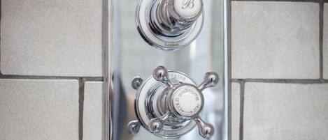 A bathroom with a chrome faucet and a wall-mounted control panel.