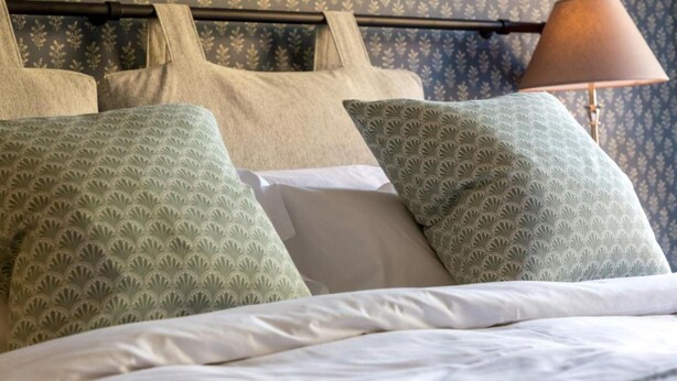 A neatly made bed with patterned pillows and a lamp beside it. - The Lion Wendlebury (Bicester)