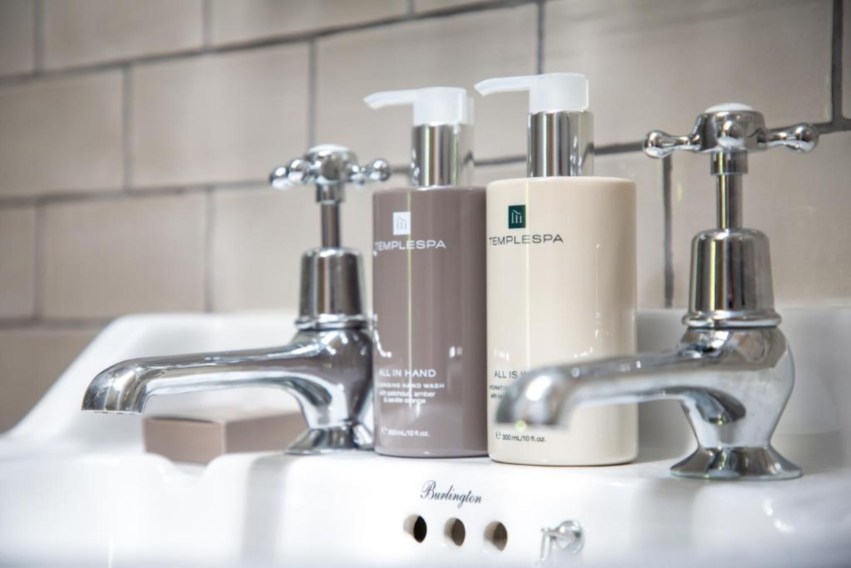 A bathroom sink with two TempleSpa hand wash bottles and a soap bar.