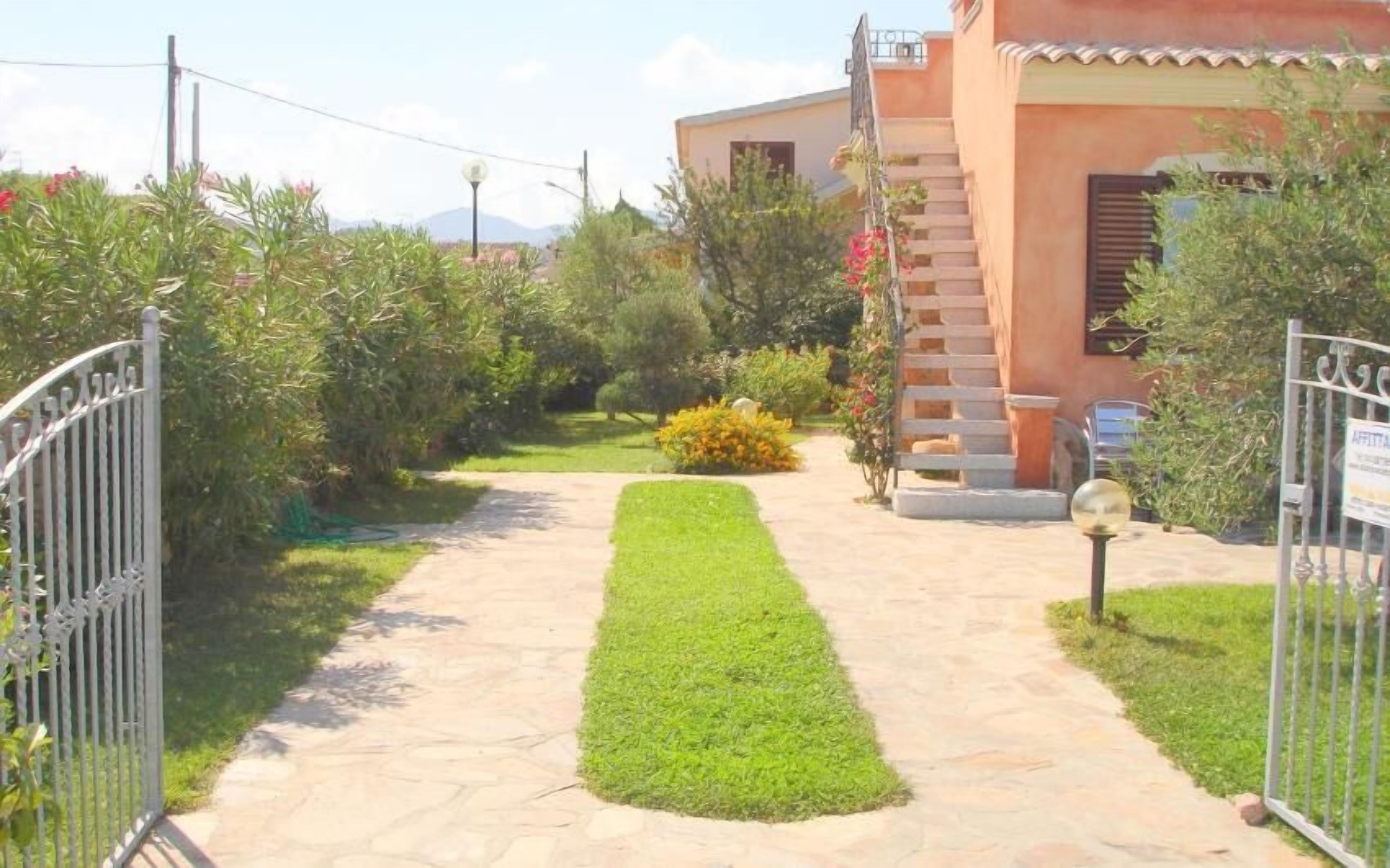 A pathway leading to a house with a garden.