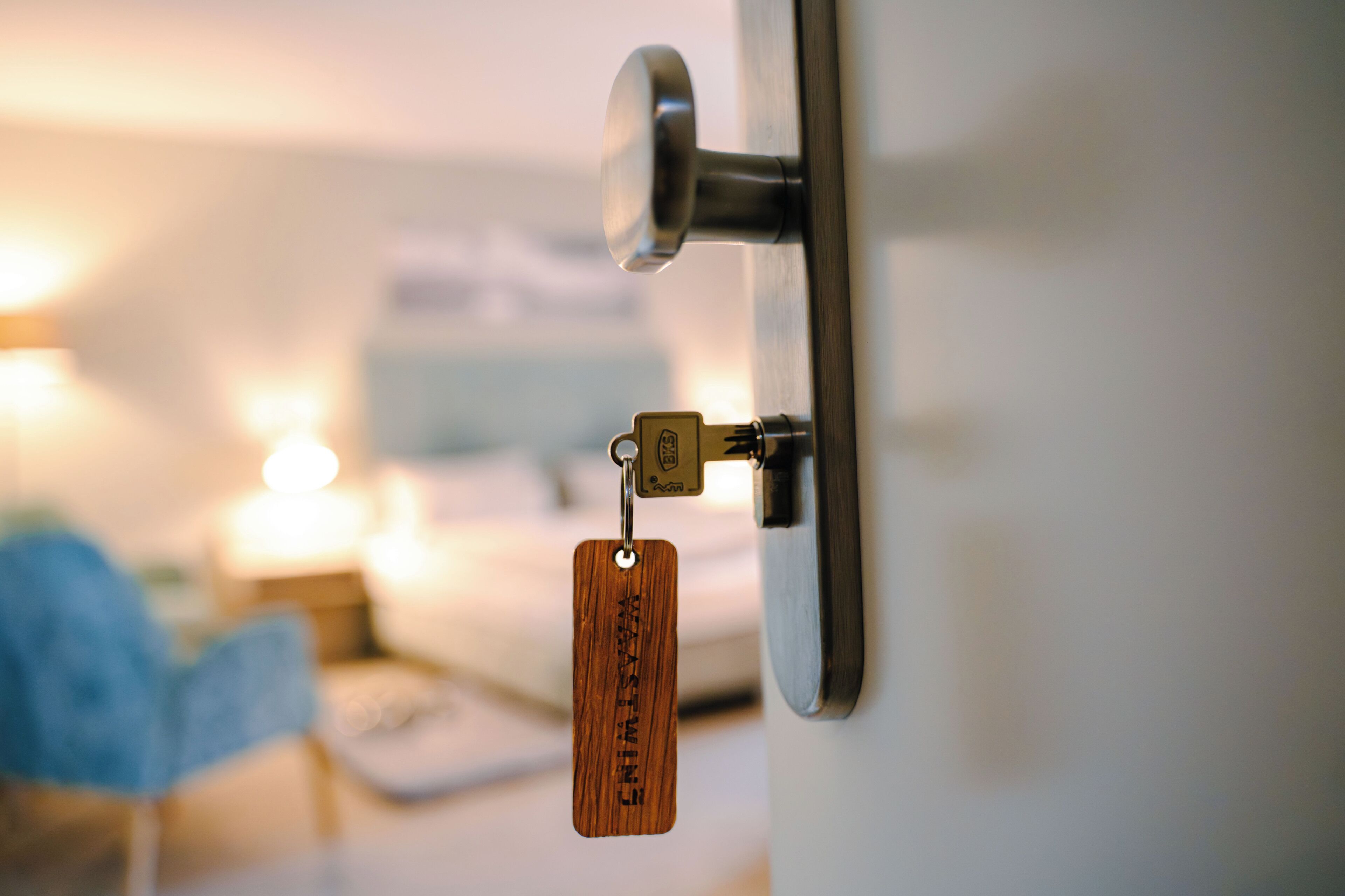 A door lock with a key and a wooden keychain.