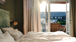A bedroom with a bed, a nightstand, and a window with curtains. - Waastwinj (Utersum)