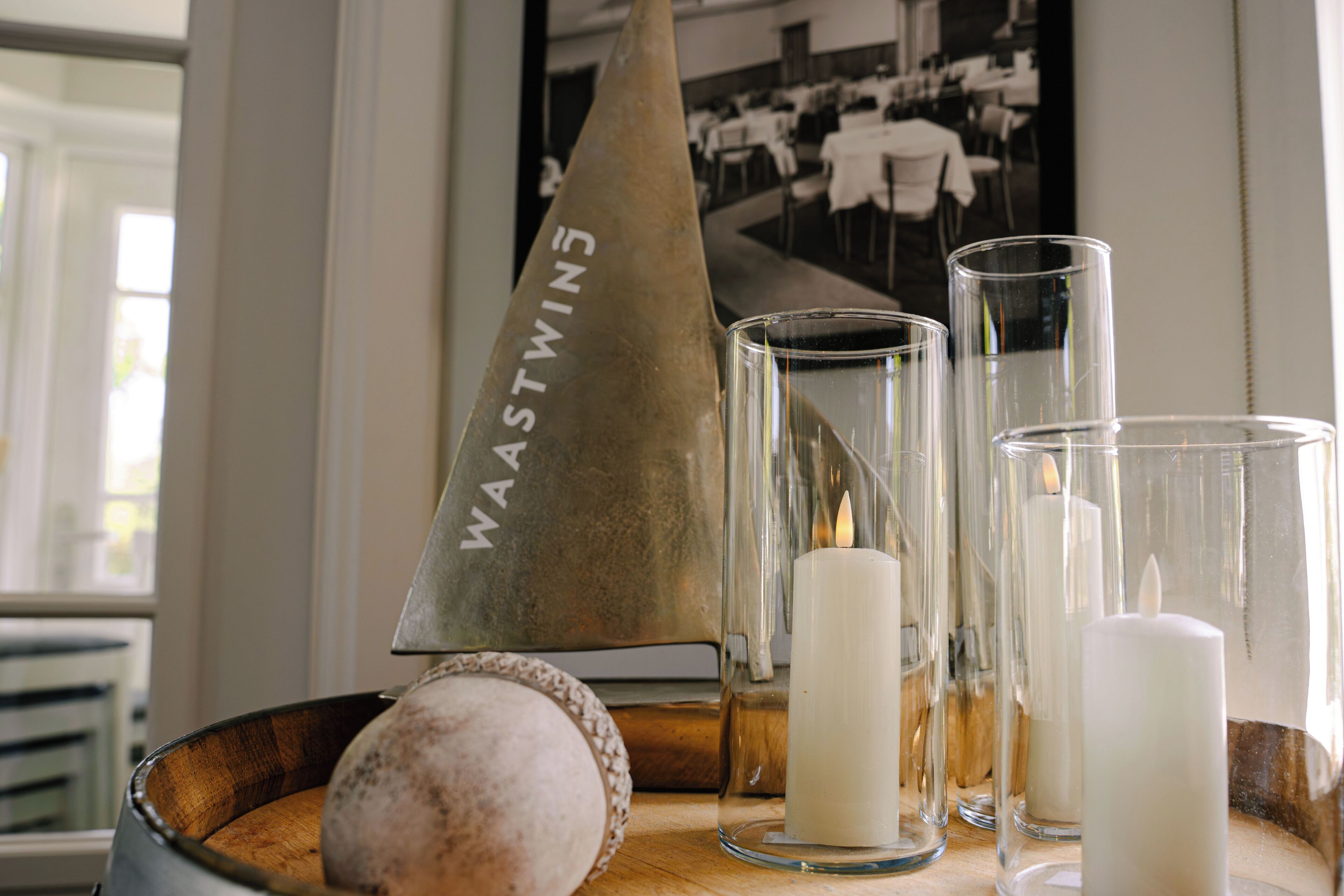 A candle in a glass holder, a candle in a glass, and a candle in a glass on a wooden surface.