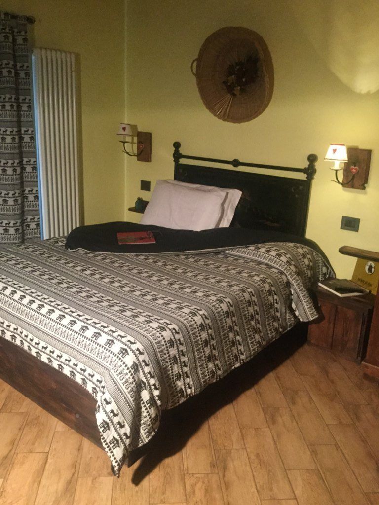 Una cama con una colcha estampada, un adorno circular en la pared y una lámpara de noche.
