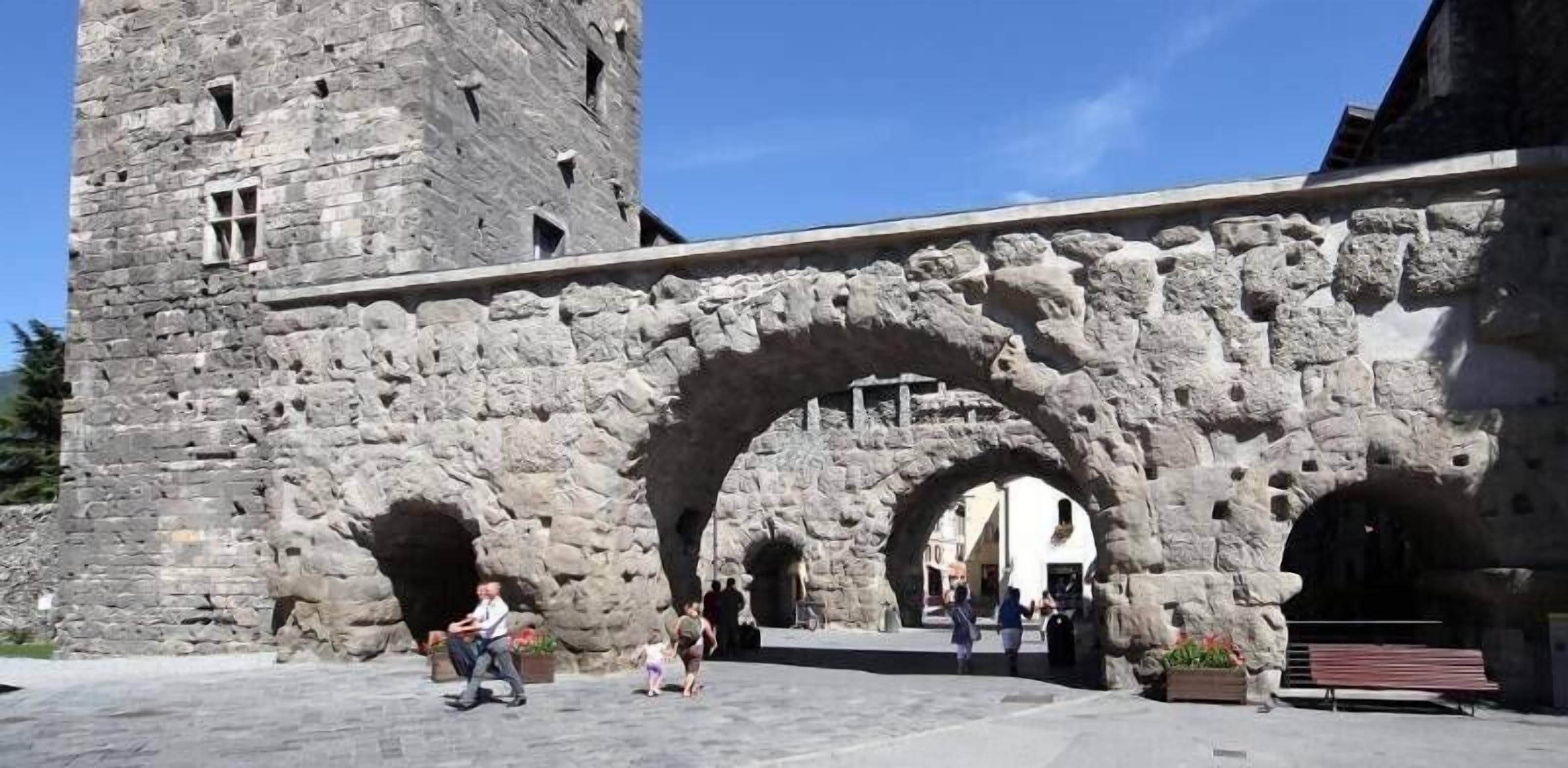 Un arco de piedra que conduce a un edificio histórico con una torre.
