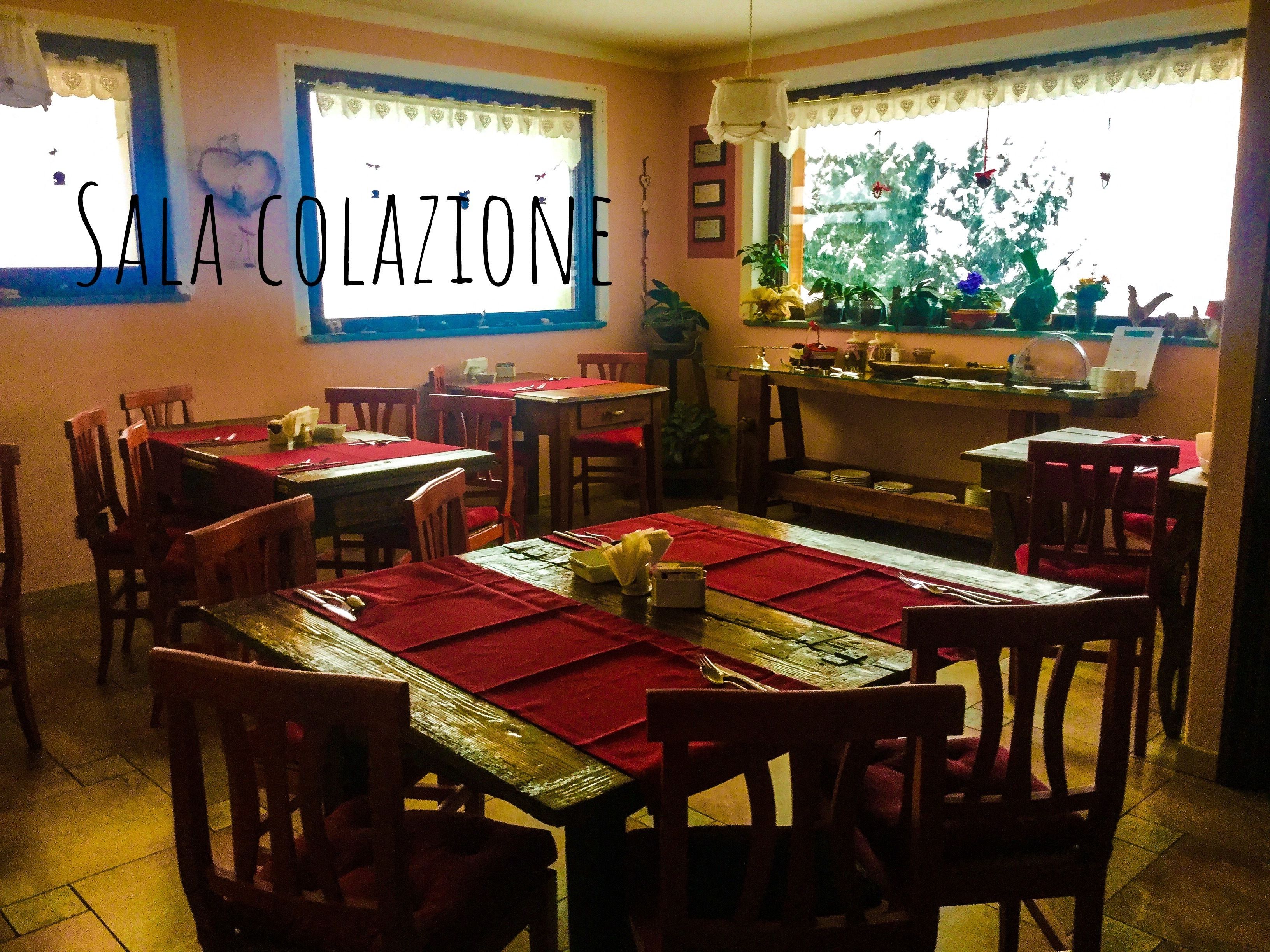 A dining area with multiple tables and chairs, a counter with a menu, and a window with curtains.