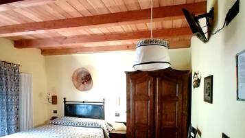 Un dormitorio con techo de madera, una cama con colcha estampada, un armario de madera y una mesa con mantel.