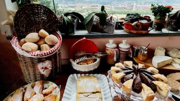 Una mesa con varios pasteles y pan, una cesta de mimbre y frascos de salsas.