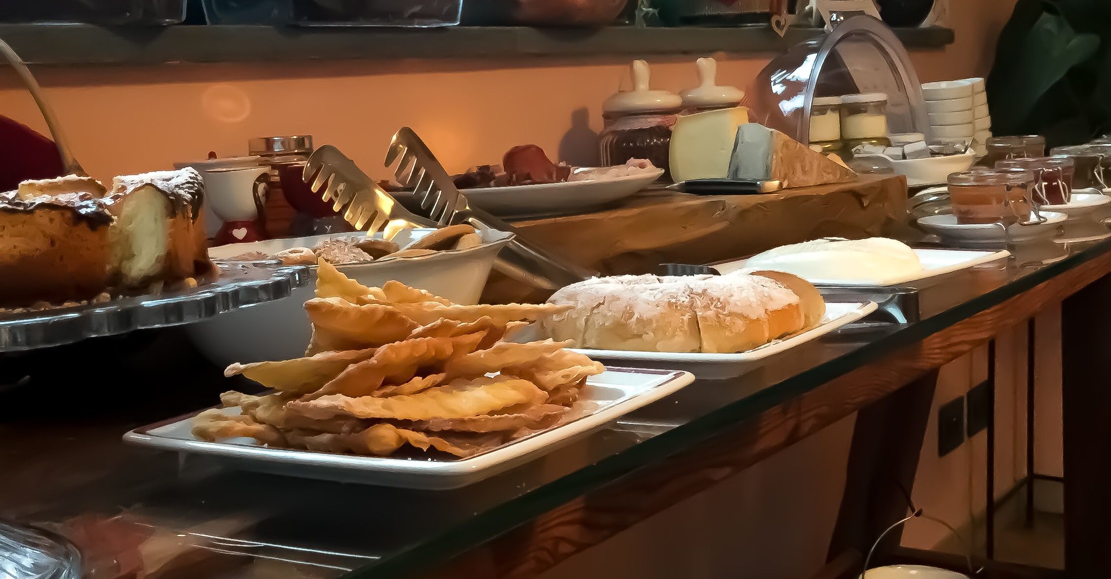 Un bufé con diversas opciones de comida, incluyendo un trozo grande de pastel, hojaldres fritos y una hogaza de pan.