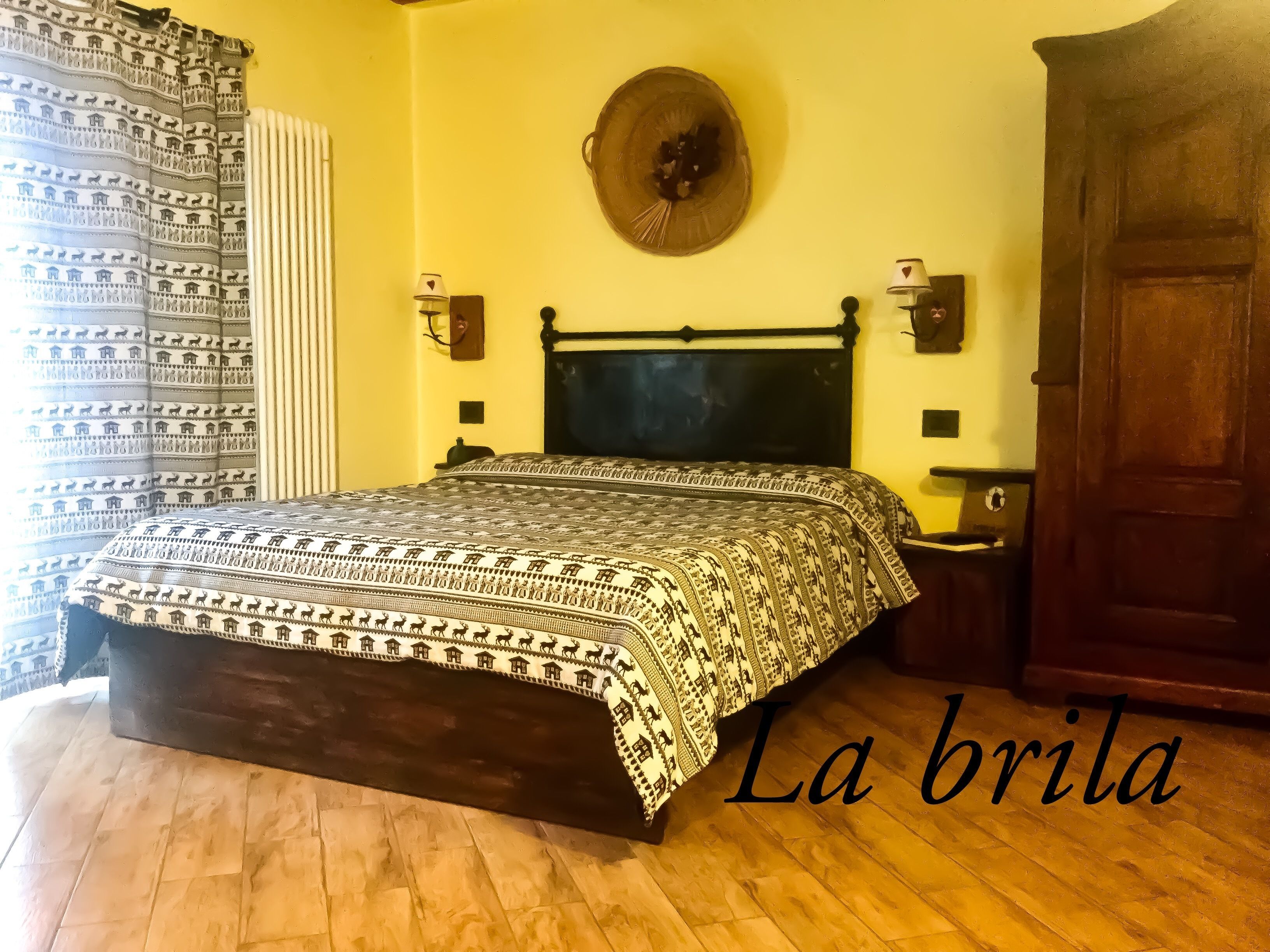 Un dormitorio con colcha estampada, cabecera de madera, lámparas de noche, un adorno circular en la pared y un armario de madera.