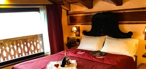 A hotel room with a large bed, a wooden headboard, and a window with a view. - Agriturismo Chevres a Cheval (Charvensod)
