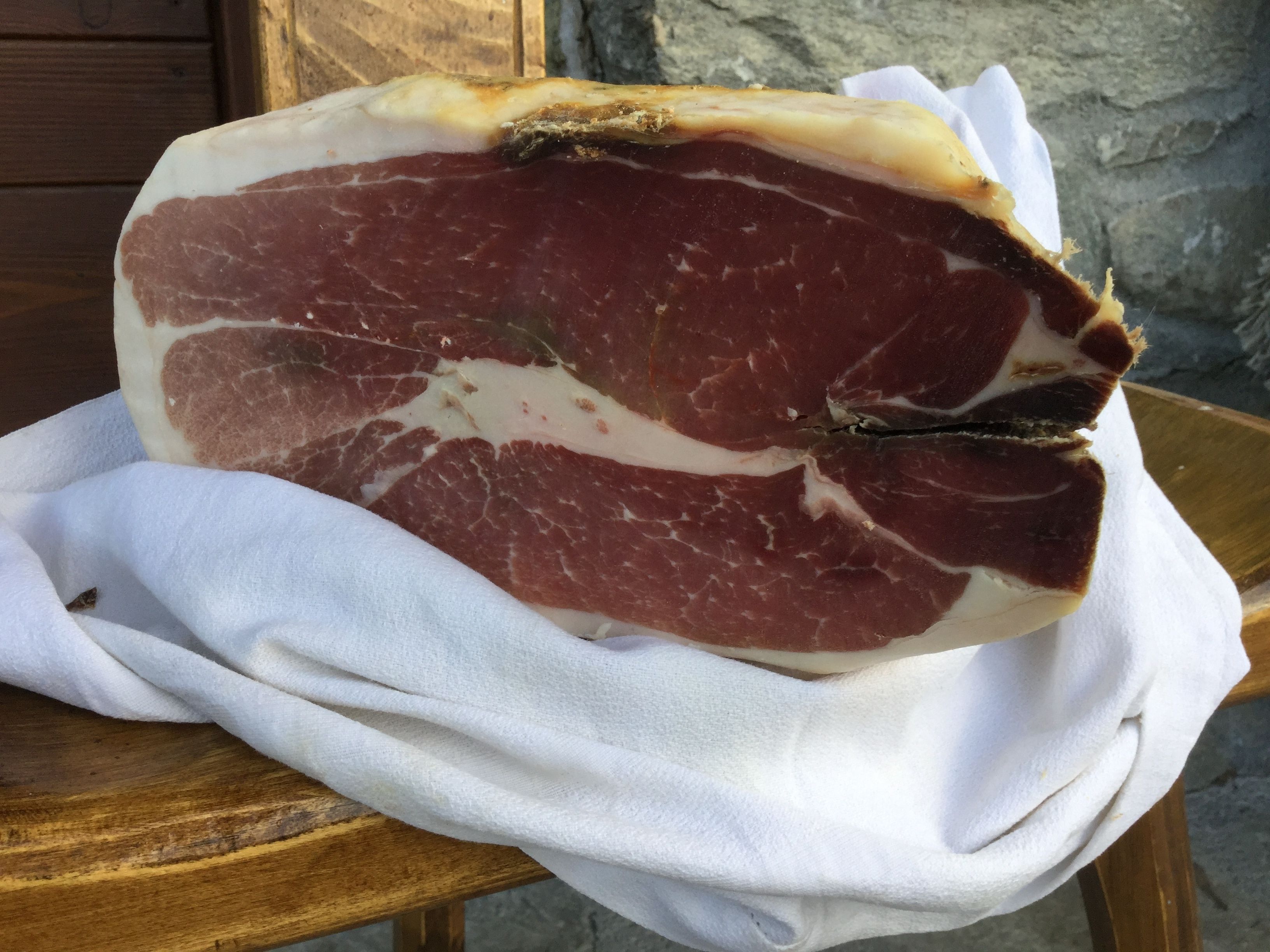 Ein großes Stück Fleisch auf einer Holztischplatte mit weißem Stoff darunter.