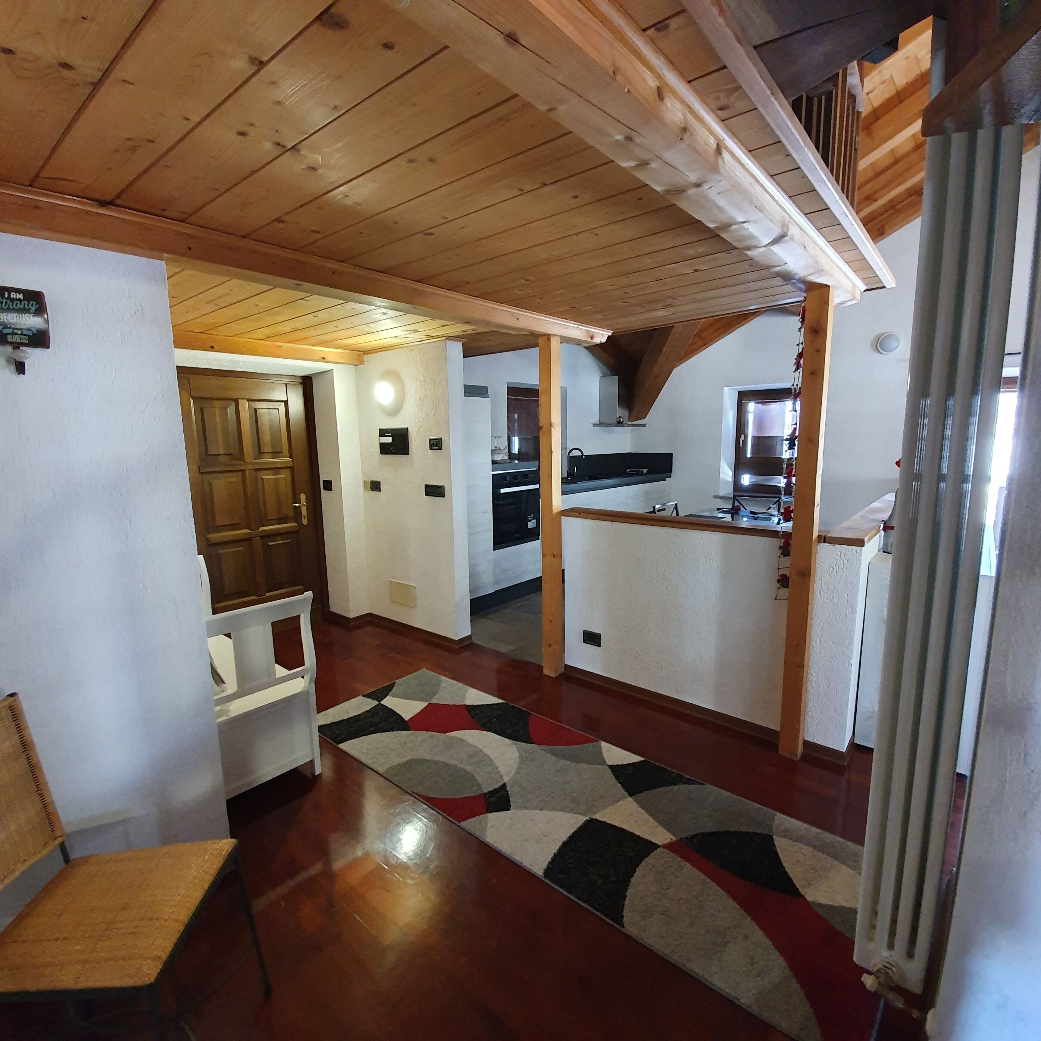 A compact kitchen with wooden beams, a built-in stove, and a refrigerator.