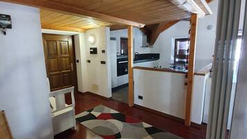 A compact kitchen with wooden beams, a built-in stove, and a refrigerator.
