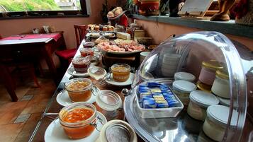 Una mesa de buffet con diversos alimentos y salsas, un expositor cubierto y vistas al exterior.