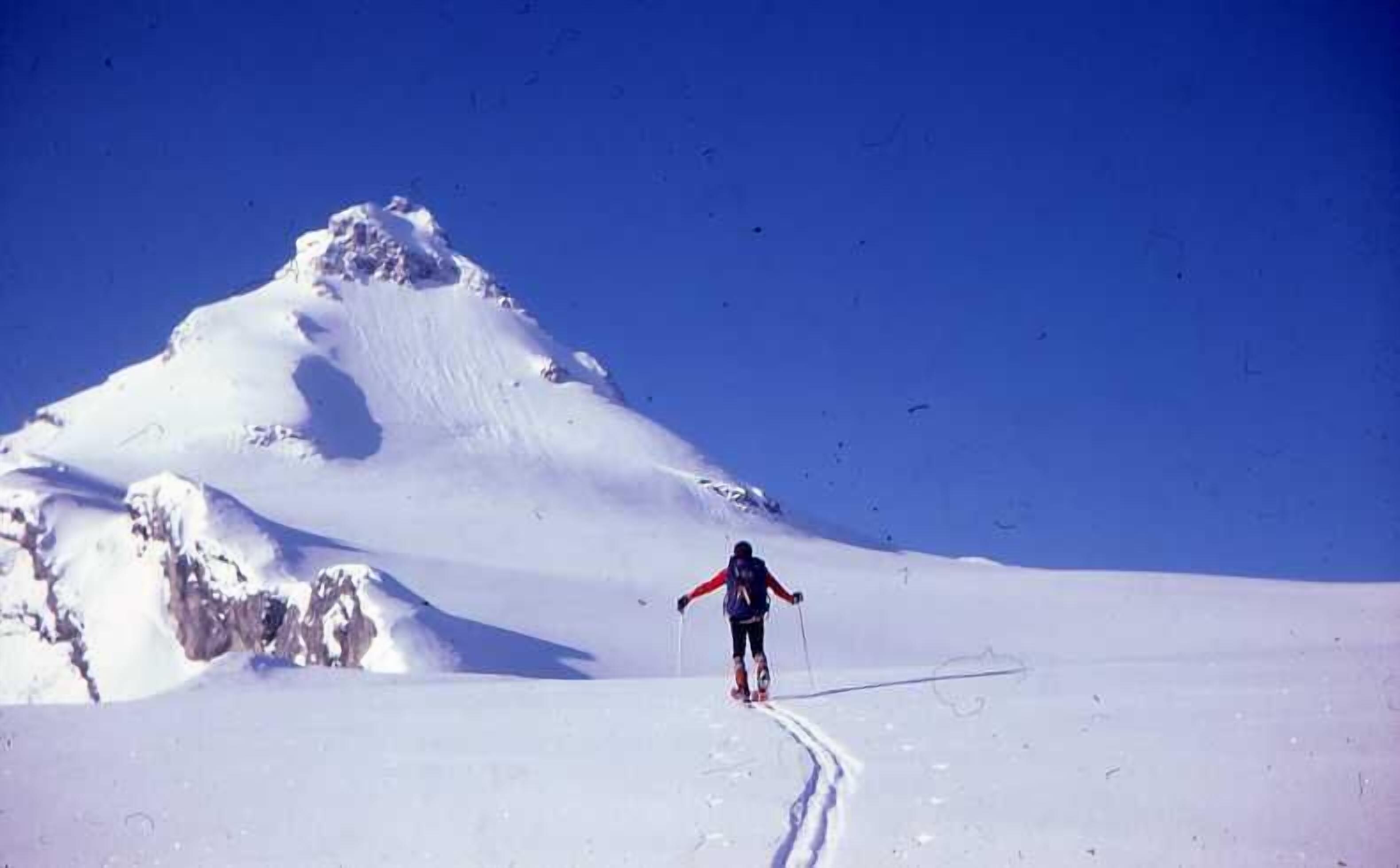 A person skiing on a snow-covered slope with a clear blue sky.