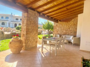 An outdoor patio with stone pillars, a dining table with chairs, and a sofa. - Solaria Apartment II (Budoni)