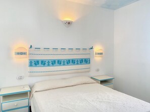 A bedroom with a bed, two bedside tables, and wall-mounted light fixtures. - Solaria Apartment II (Budoni)