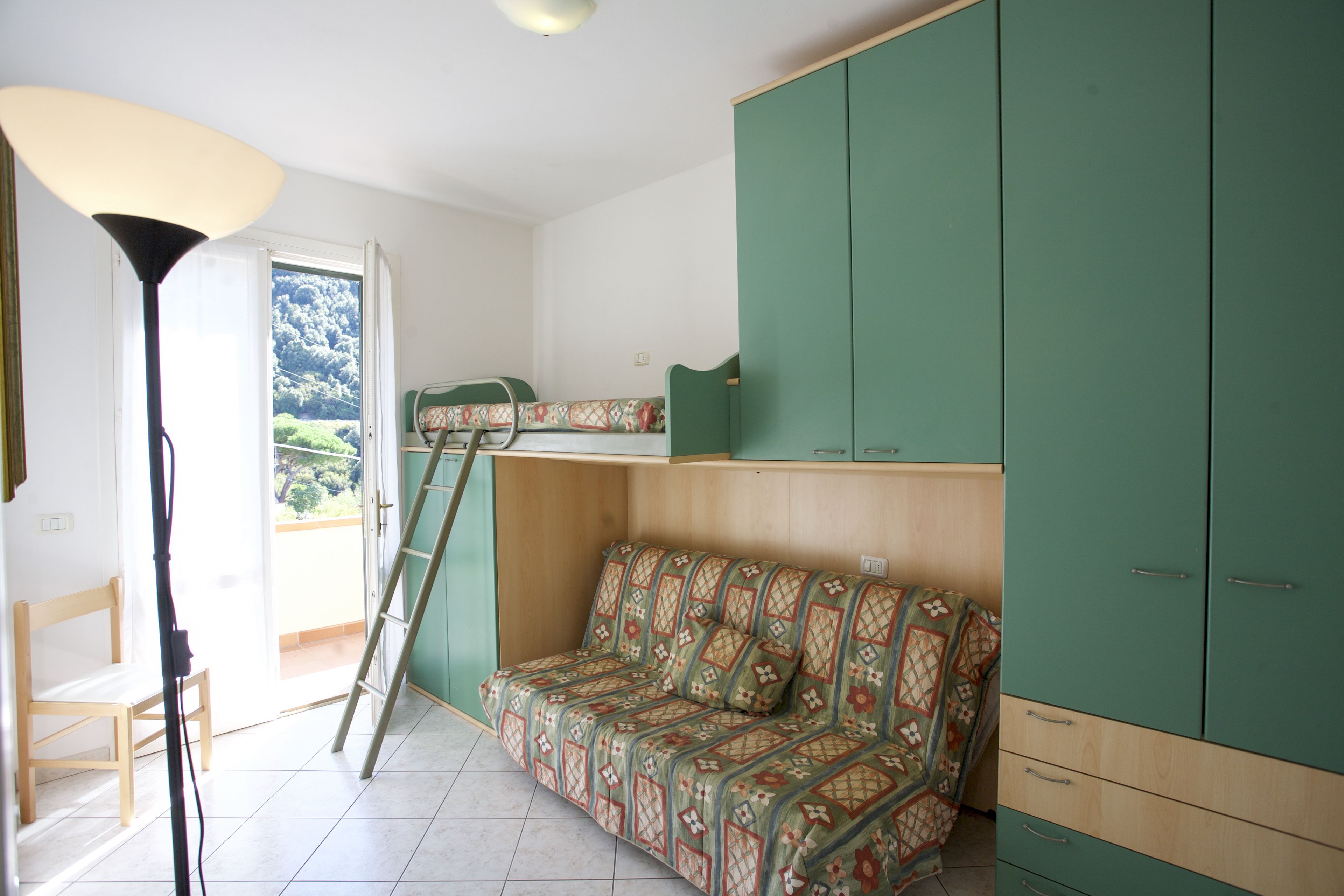 A room with a green sofa, a wooden ladder, and a green cabinet.