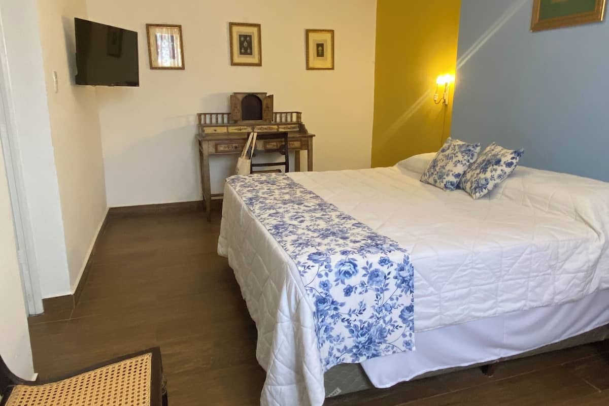 Un dormitorio con cama, escritorio, silla y televisor.