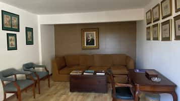A living room with a brown sofa, wooden chairs, a coffee table, and a wall-mounted picture frame.