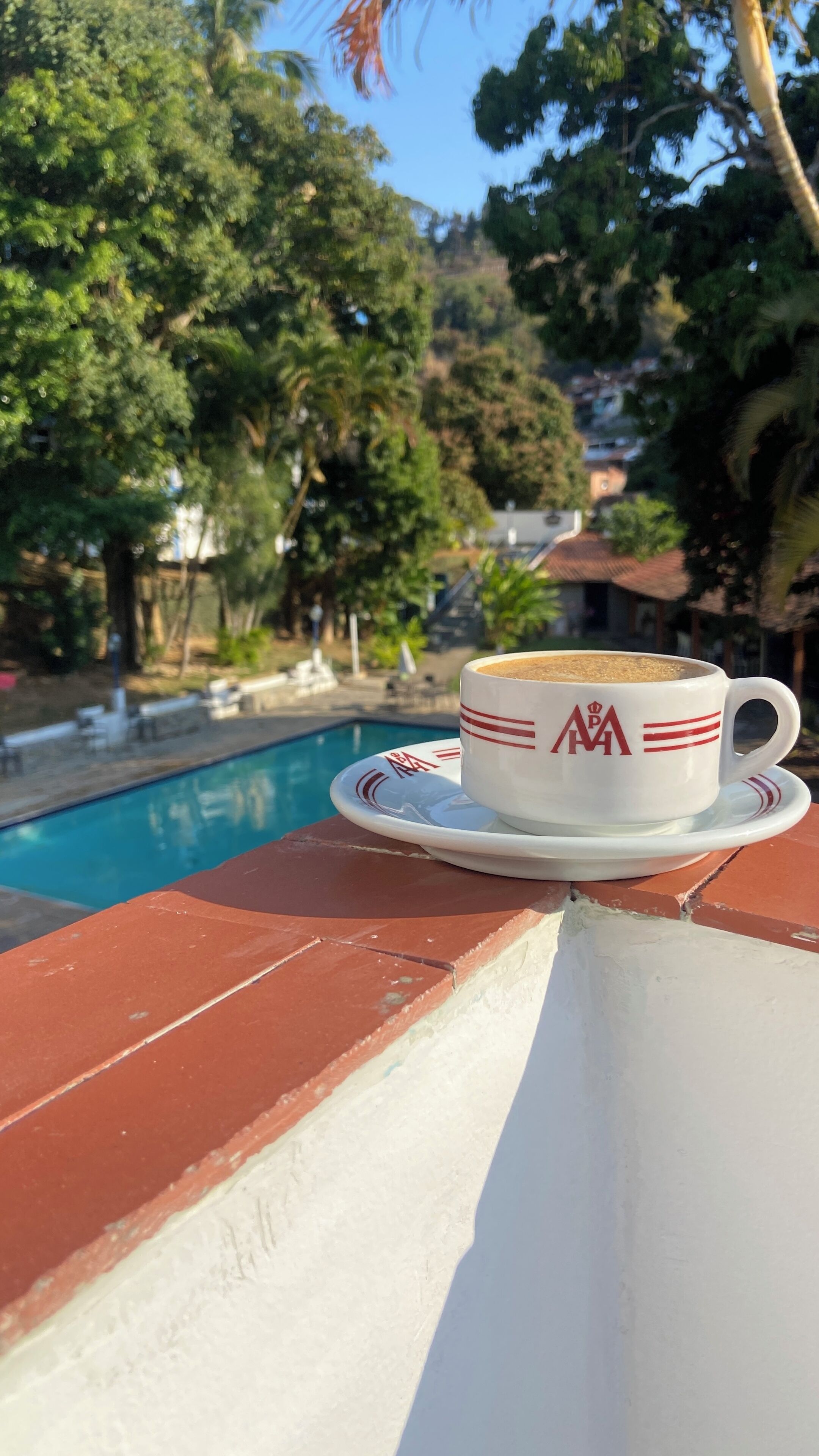 A white cup with a logo on a table by a poolside.