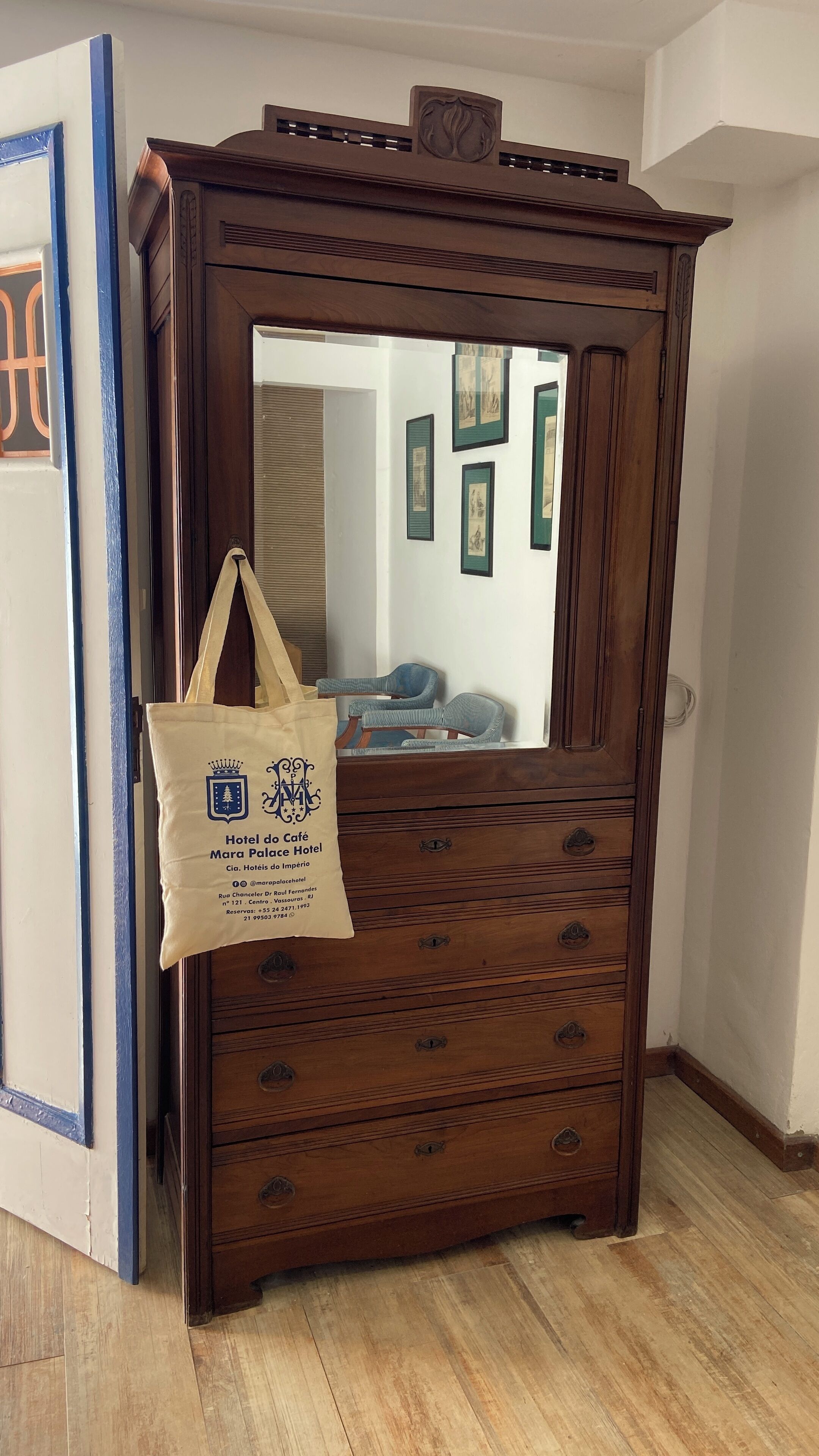Ein Holzschrank, eine beige Tragetasche und ein blau gerahmtes Bild an der Wand.