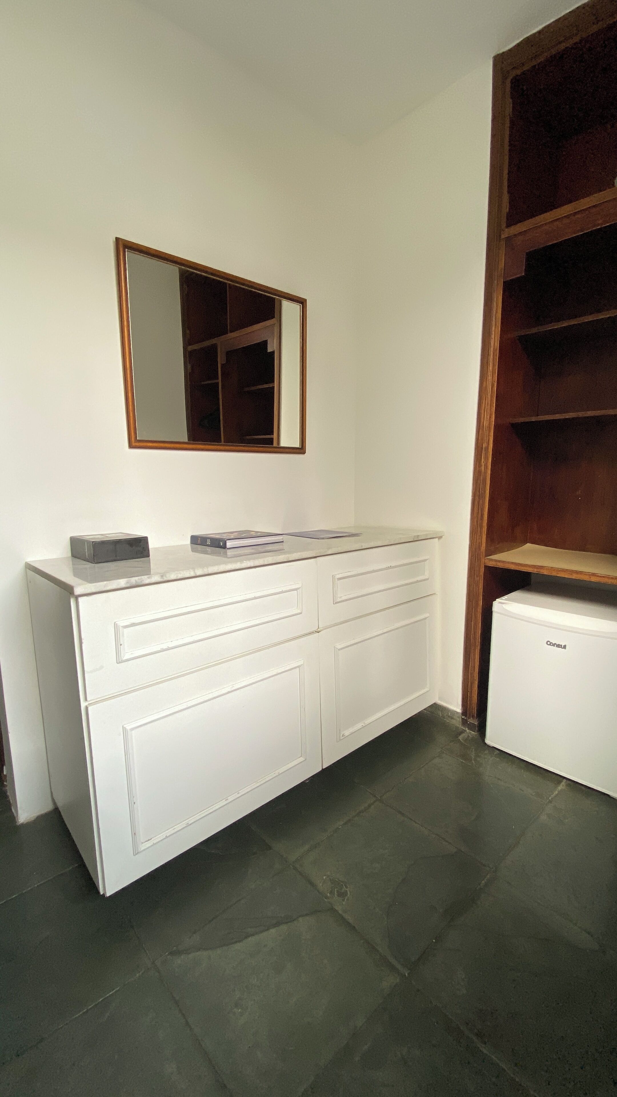 A white cabinet with drawers, a small refrigerator, and a wooden shelf unit.