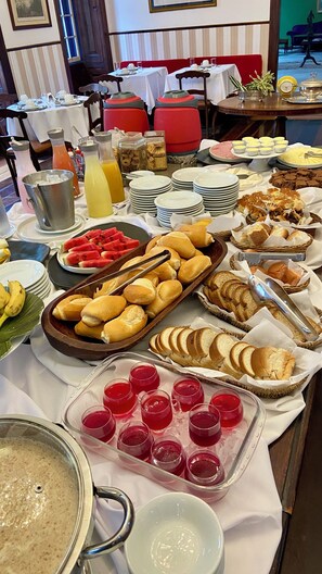 A buffet with various food items, including bread, pastries, and fruit. - Mara Palace Hotel (Vassouras)