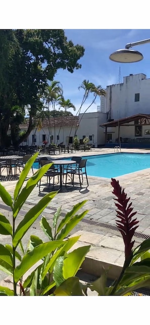 Una piscina al aire libre, sombrillas, sillones reclinables de piscina