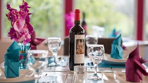 Una mesa de comedor con copas de vino, una botella de vino y un jarrón con flores rosas.