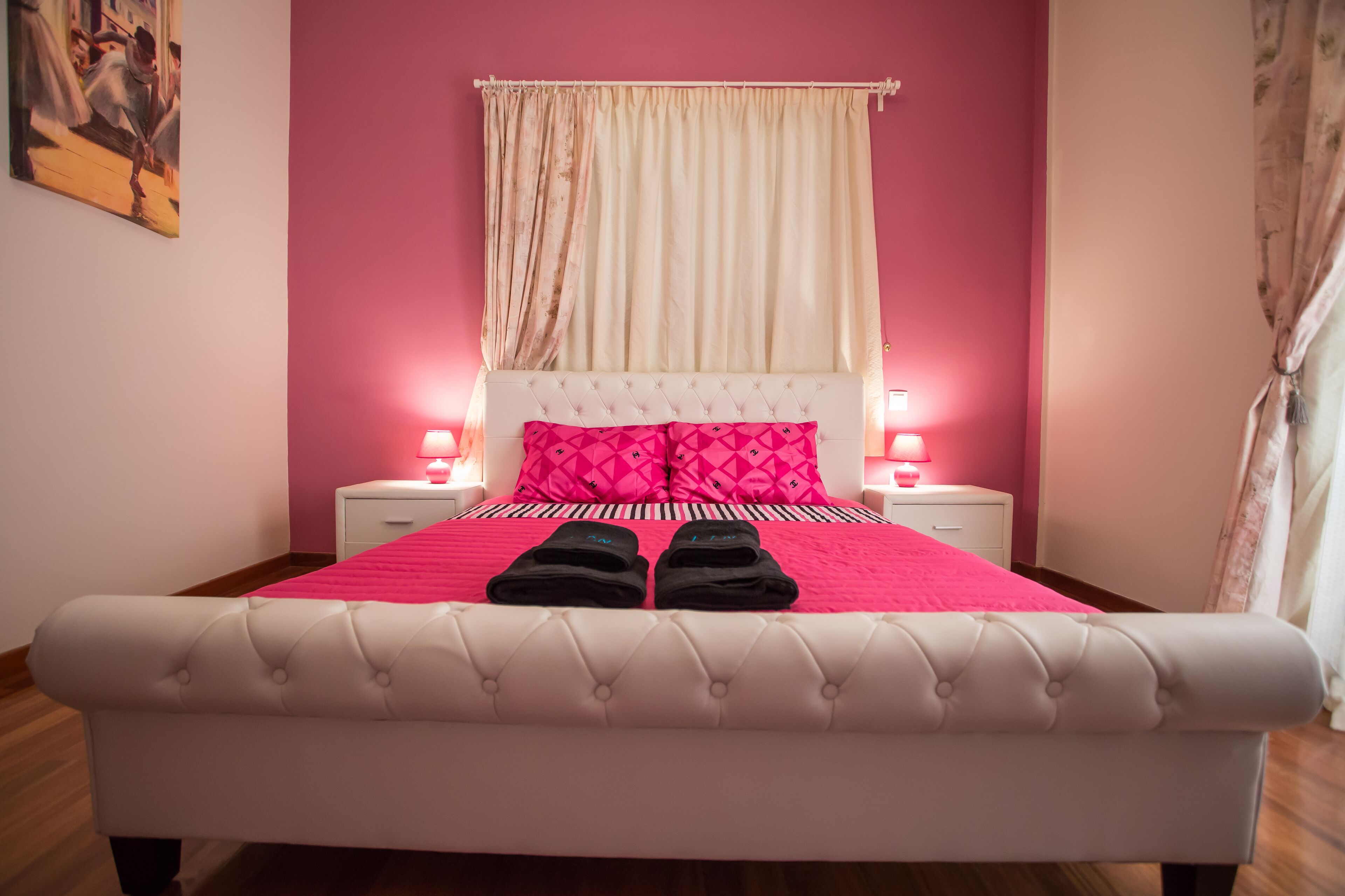 A bed with a pink bedspread and pillows, two bedside lamps, and a white headboard.