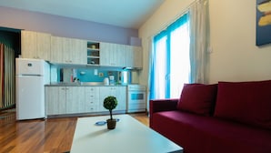 Un espacio habitable compacto con kitchenette, un sofá rojo y una pequeña mesa con una planta.