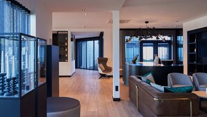 Un salon moderne avec un plancher en bois, un ensemble de canapés, une vitrine et un coin repas agrémenté d’une grande fenêtre.