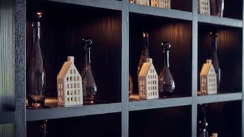 Una estantería de madera oscura con varias botellas de vidrio y pequeñas figuras blancas con forma de casa.