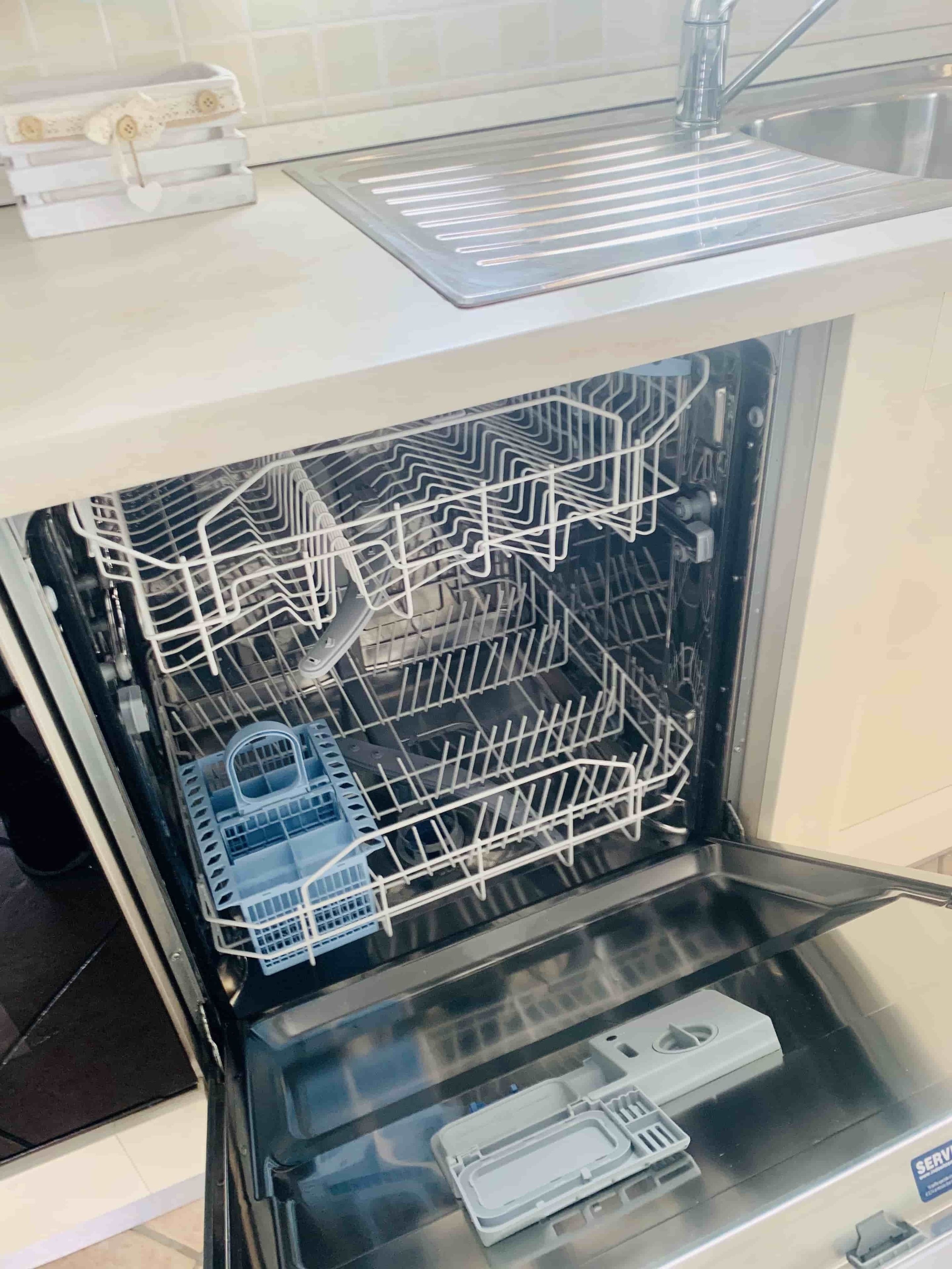 An open dishwasher with racks and utensils inside.