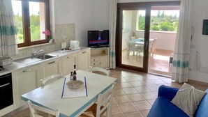 A compact kitchen with a dining area, a TV, and a sofa. - Solaria Apartment VIII (Budoni)
