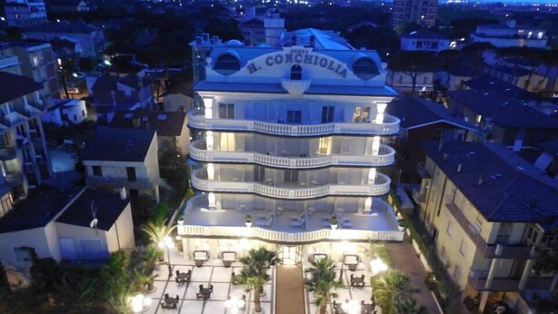 A multi-story hotel with a central courtyard, balconies, and a sign reading "B. Conchiolia". - Hotel Conchiglia (Cervia)